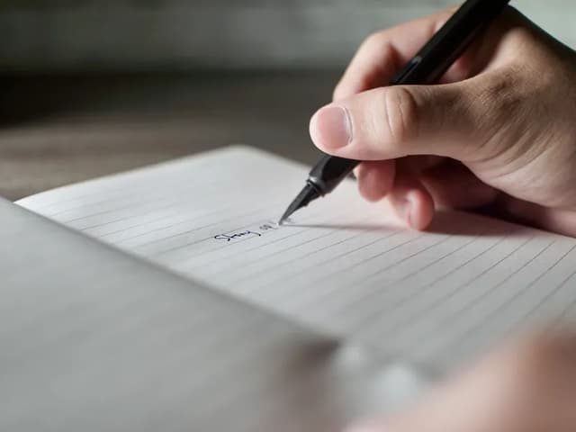 A hand writing with a fine pen on lined paper