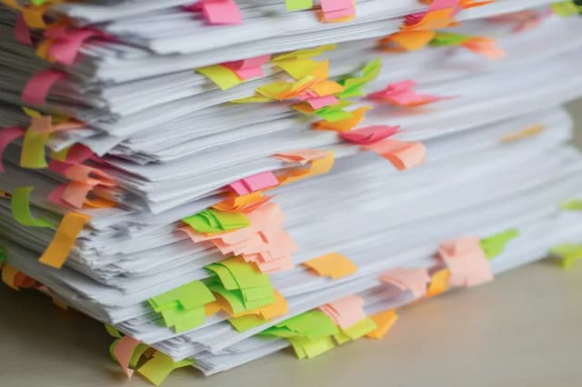 A thick stack of papers marked with coloured sticky tabs