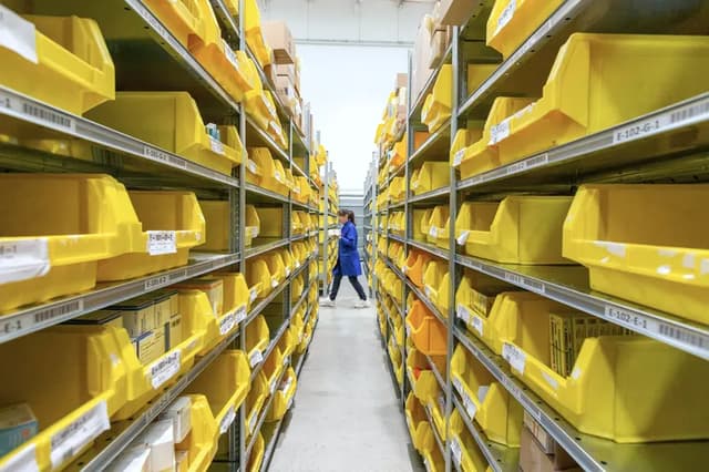 A long aisle of yellow parts bins on warehouse shelves