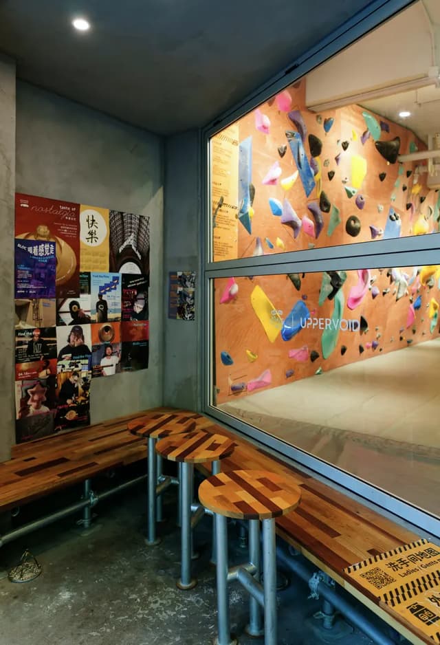 Wooden stools beside an indoor climbing wall